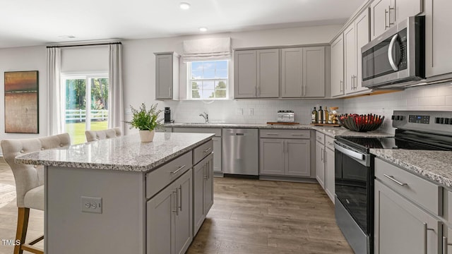 kitchen featuring appliances with stainless steel finishes, a kitchen bar, gray cabinets, and a kitchen island