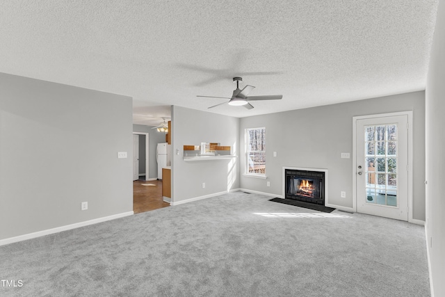 unfurnished living room with ceiling fan, light carpet, and a textured ceiling