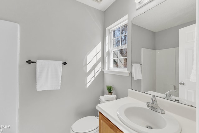 bathroom featuring walk in shower, vanity, and toilet