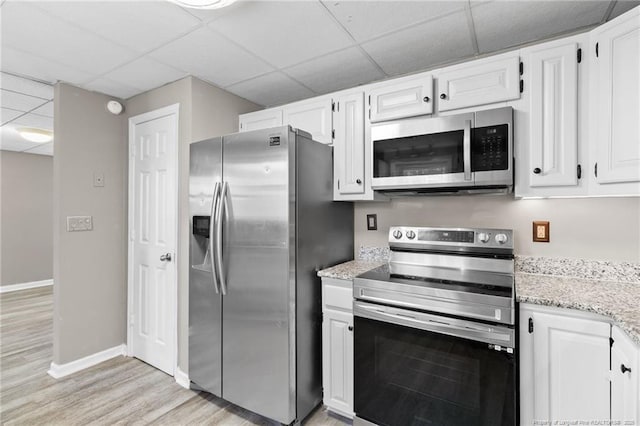 kitchen featuring light wood finished floors, appliances with stainless steel finishes, a paneled ceiling, and white cabinetry