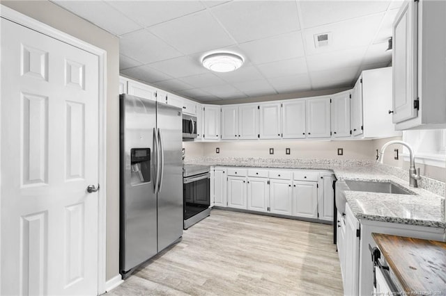 kitchen featuring white cabinetry, light wood-style floors, visible vents, appliances with stainless steel finishes, and light stone countertops