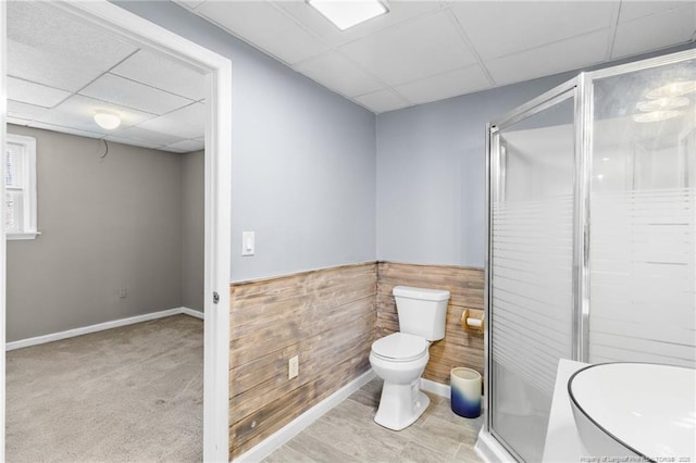 bathroom with a stall shower, wainscoting, a drop ceiling, and toilet