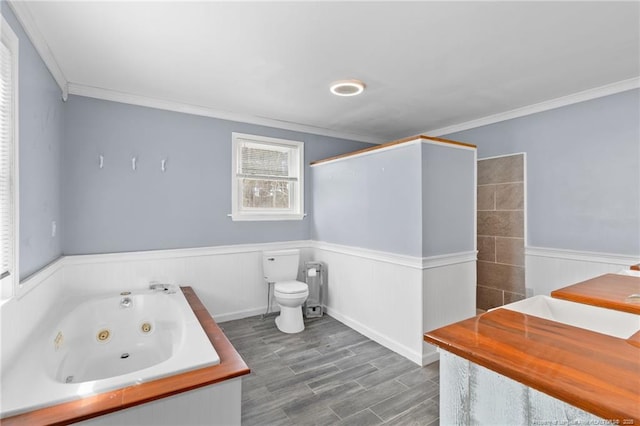 bathroom with toilet, a wainscoted wall, ornamental molding, and a jetted tub