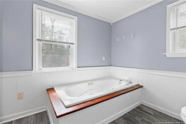 bathroom with a healthy amount of sunlight, a garden tub, wood finished floors, and a wainscoted wall