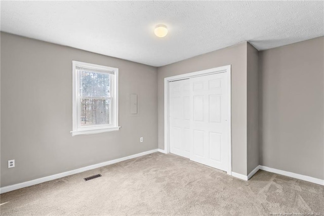 unfurnished bedroom featuring baseboards, a closet, visible vents, and carpet flooring