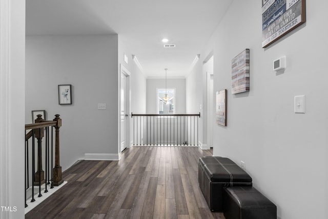 corridor with ornamental molding, dark wood-type flooring, and a chandelier