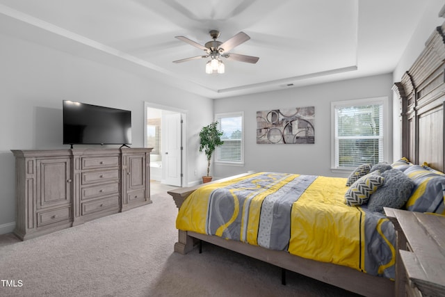carpeted bedroom featuring ensuite bathroom, ceiling fan, and a raised ceiling