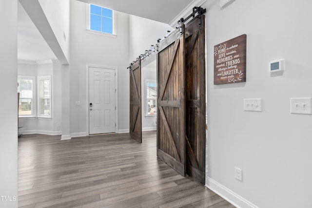 entryway with hardwood / wood-style flooring, crown molding, and a barn door