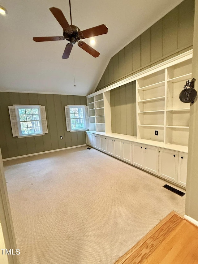 unfurnished living room featuring ceiling fan, built in features, lofted ceiling, and light carpet