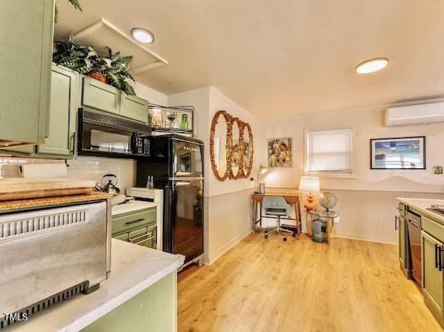 kitchen featuring black appliances, light hardwood / wood-style flooring, a wall mounted AC, and green cabinetry