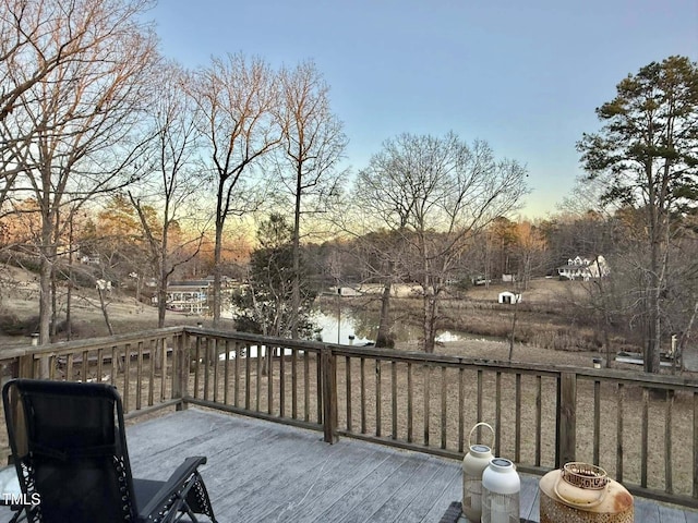 deck at dusk featuring a water view