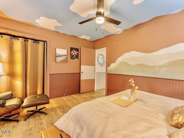 bedroom featuring wood walls, ceiling fan, and light hardwood / wood-style flooring