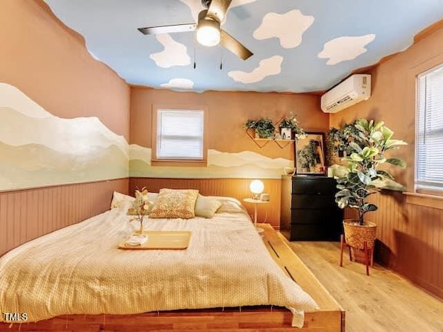 bedroom with hardwood / wood-style floors, wooden walls, a wall unit AC, and ceiling fan