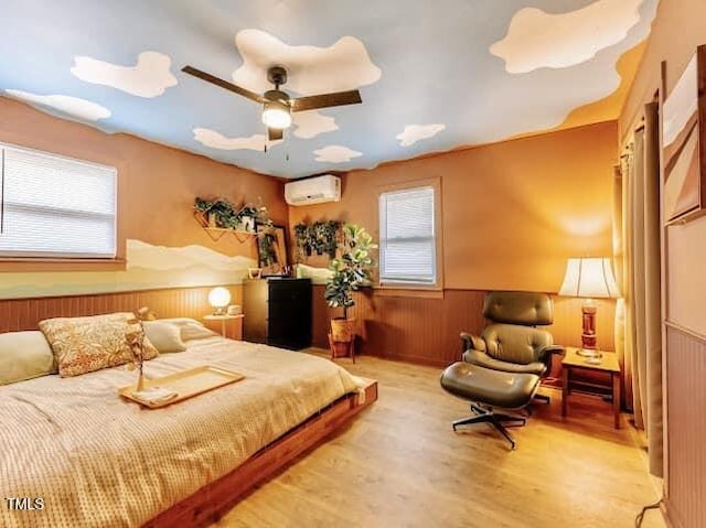 bedroom with a wall mounted air conditioner, wooden walls, multiple windows, and light hardwood / wood-style flooring