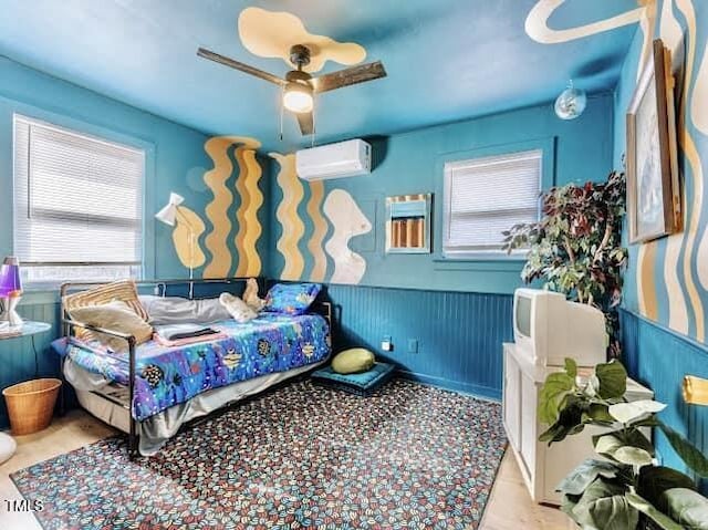 bedroom with ceiling fan and a wall mounted air conditioner