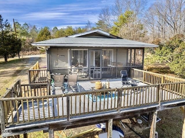 back of property with a sunroom and a swimming pool side deck