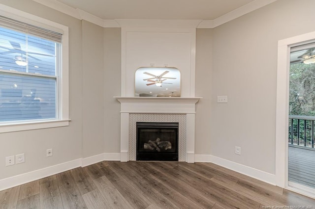 unfurnished living room featuring ornamental molding, ceiling fan, a tile fireplace, and wood-type flooring