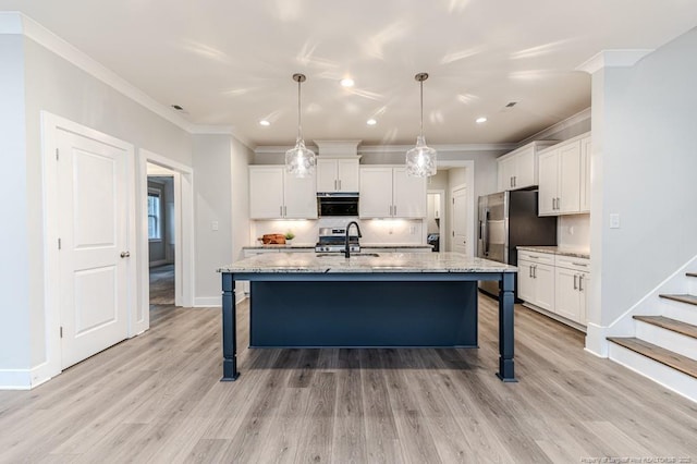 kitchen featuring white cabinetry, a kitchen island with sink, stainless steel appliances, decorative light fixtures, and light stone countertops