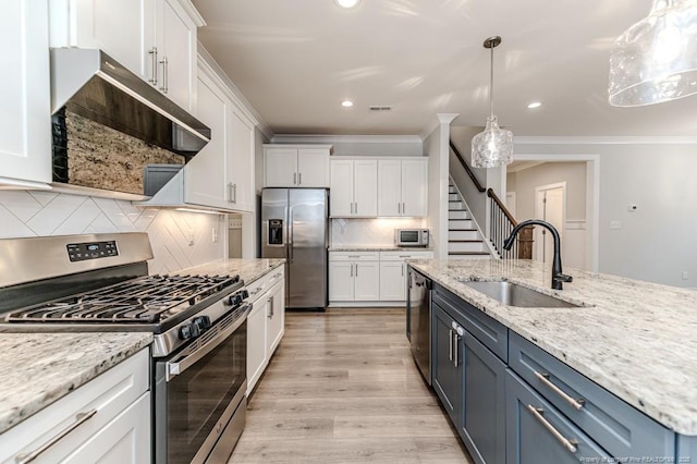 kitchen with appliances with stainless steel finishes, blue cabinetry, pendant lighting, sink, and white cabinetry