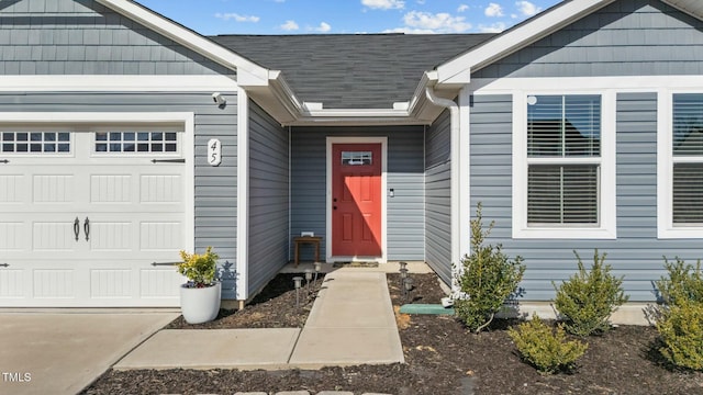 doorway to property featuring a garage and roof with shingles