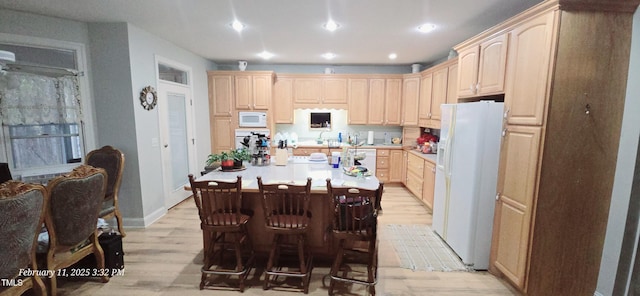 kitchen featuring light brown cabinetry, white appliances, and light countertops