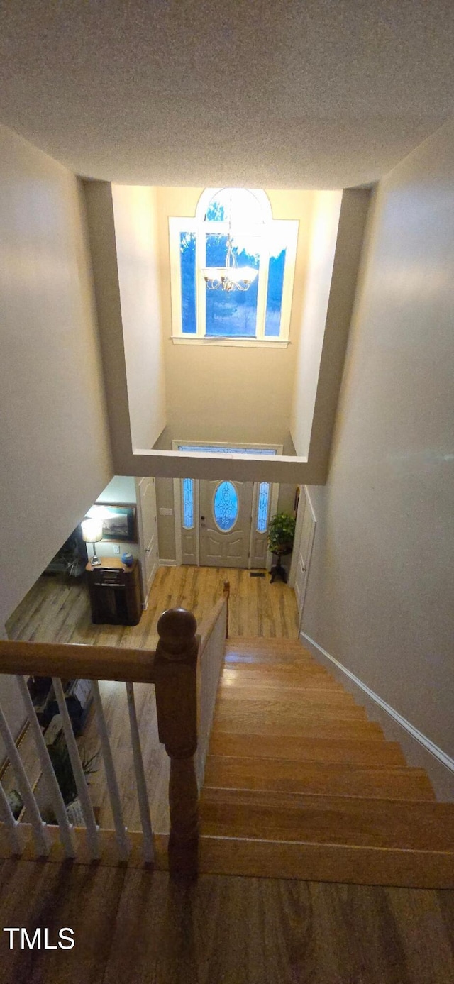 stairs featuring a textured ceiling and wood finished floors