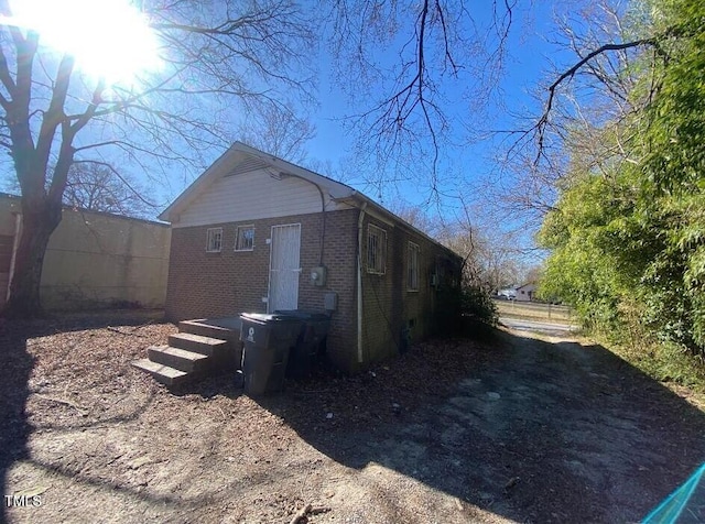 view of side of home featuring fence and brick siding