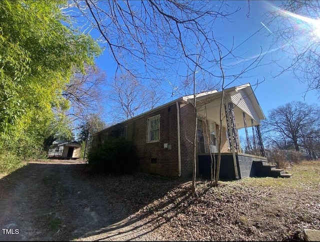 view of home's exterior featuring a porch, crawl space, and brick siding