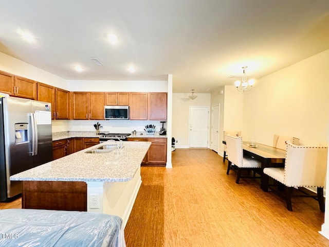 kitchen featuring hanging light fixtures, appliances with stainless steel finishes, a kitchen island with sink, and sink