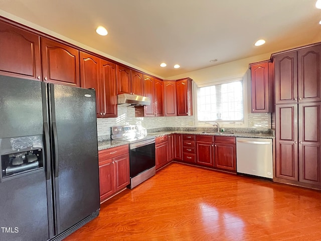 kitchen featuring wood-type flooring, sink, backsplash, stainless steel appliances, and light stone countertops