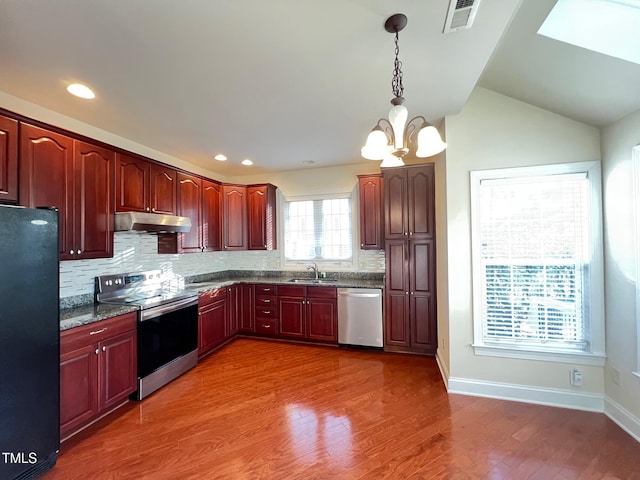 kitchen with pendant lighting, sink, appliances with stainless steel finishes, a notable chandelier, and dark stone counters