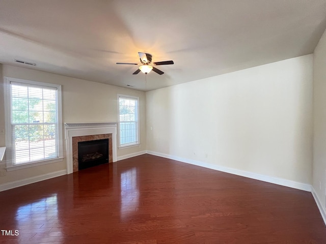 unfurnished living room with dark wood-type flooring, ceiling fan, plenty of natural light, and a high end fireplace