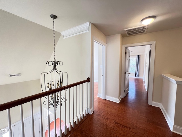 corridor featuring dark wood-type flooring and an inviting chandelier