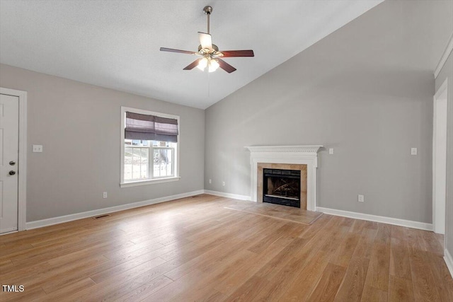 unfurnished living room with visible vents, light wood-type flooring, vaulted ceiling, a fireplace, and a ceiling fan