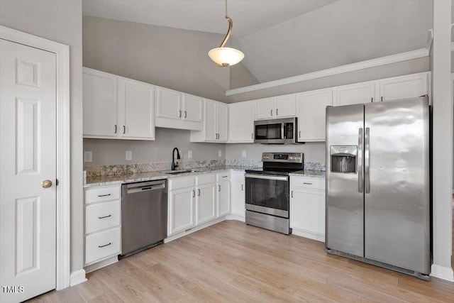 kitchen featuring light stone counters, light wood finished floors, appliances with stainless steel finishes, and white cabinetry