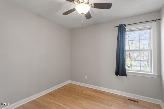 spare room with visible vents, ceiling fan, baseboards, and light wood-style floors