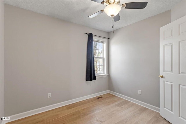 unfurnished room featuring light wood finished floors, visible vents, baseboards, ceiling fan, and a textured ceiling