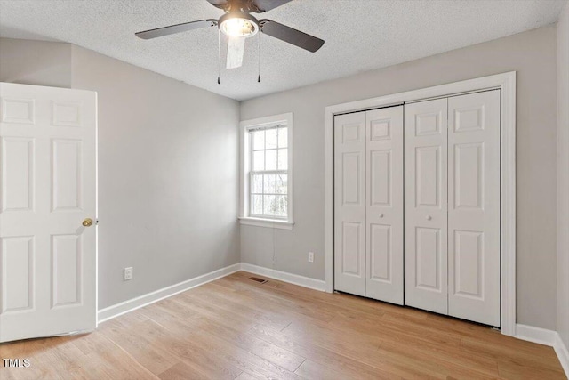 unfurnished bedroom featuring baseboards, light wood finished floors, ceiling fan, a closet, and a textured ceiling