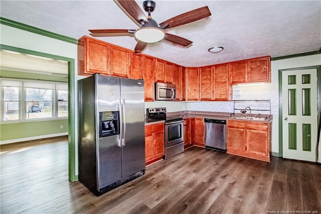 kitchen with dark wood-type flooring, sink, crown molding, appliances with stainless steel finishes, and ceiling fan