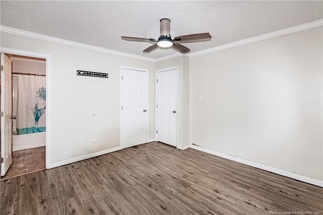 unfurnished bedroom featuring dark hardwood / wood-style flooring, crown molding, ensuite bath, and ceiling fan