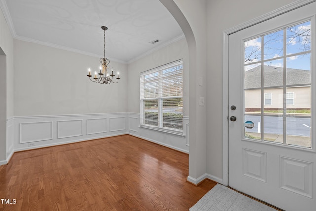 interior space with wood-type flooring, a notable chandelier, and crown molding