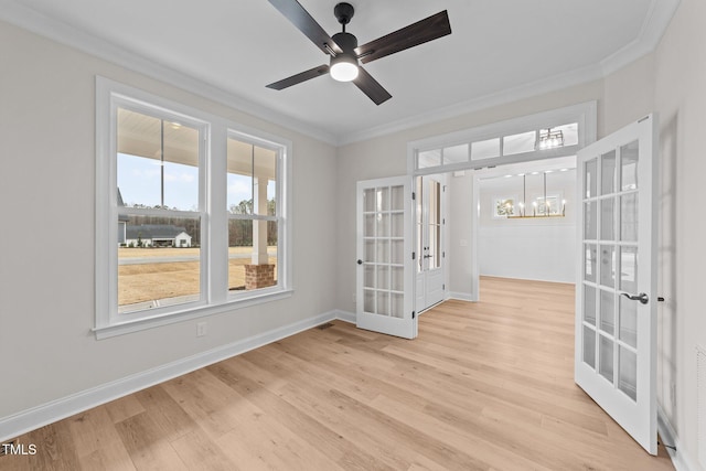 unfurnished room featuring ornamental molding, ceiling fan with notable chandelier, light hardwood / wood-style flooring, and french doors