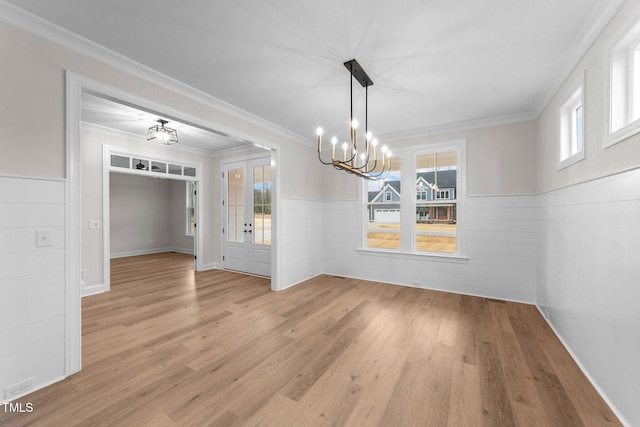 unfurnished dining area with ornamental molding, a chandelier, and light wood-type flooring