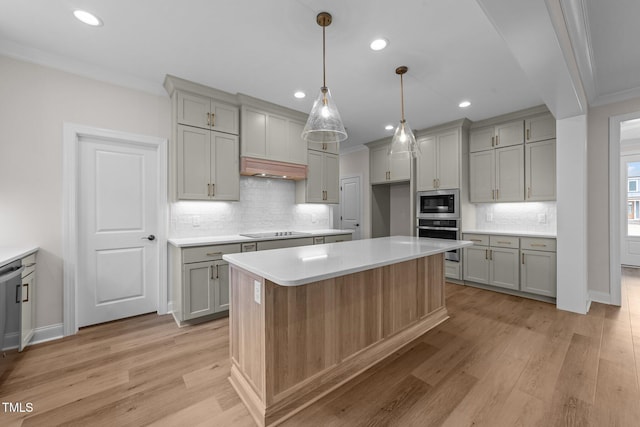 kitchen with appliances with stainless steel finishes, gray cabinets, light hardwood / wood-style floors, and a kitchen island