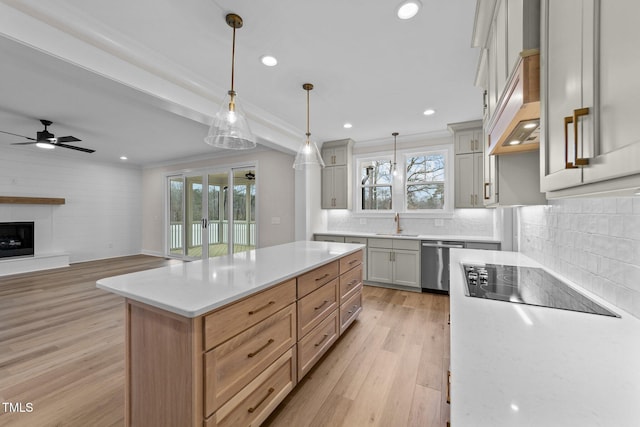 kitchen featuring a kitchen island, decorative light fixtures, dishwasher, sink, and light hardwood / wood-style flooring