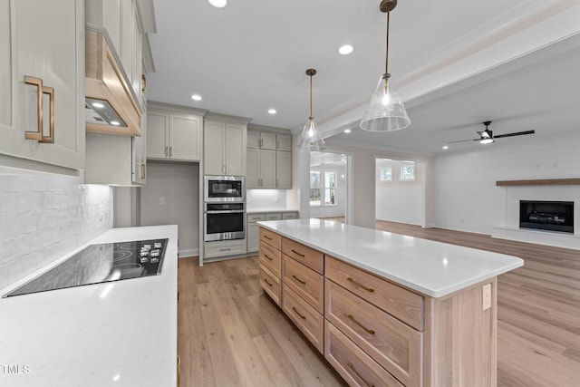 kitchen featuring appliances with stainless steel finishes, decorative light fixtures, a center island, and light hardwood / wood-style floors