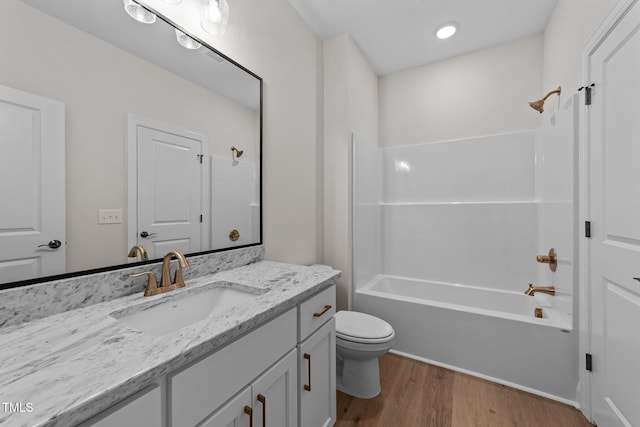 full bathroom with hardwood / wood-style flooring, vanity, tub / shower combination, and toilet