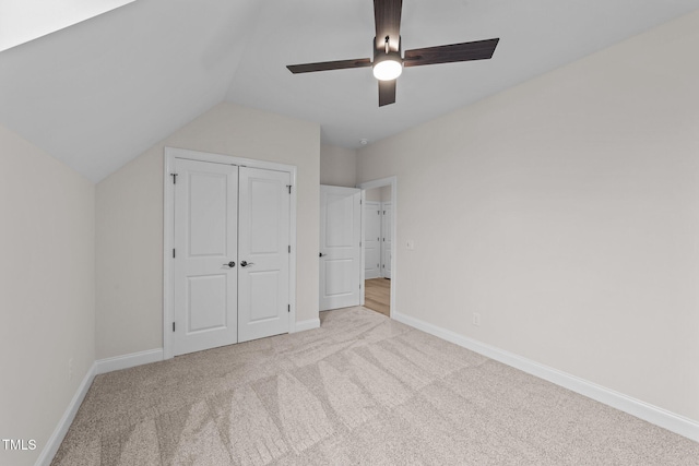 unfurnished bedroom with light carpet, vaulted ceiling, a closet, and ceiling fan