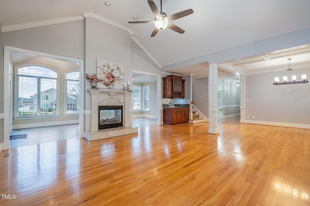 unfurnished living room with crown molding, high vaulted ceiling, a fireplace, ceiling fan with notable chandelier, and light wood-type flooring