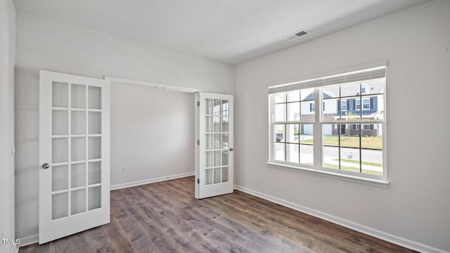 empty room featuring dark wood-type flooring, a wealth of natural light, and french doors